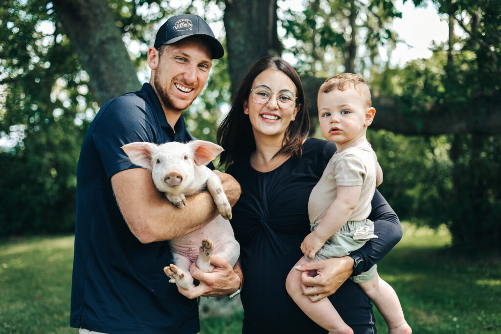 Famille de la Ferme Villoise tenant un porcelet, illustrant les velurs de respect, de transmission et d'agriculture durable au Saguenay Lac-Saint-Jean